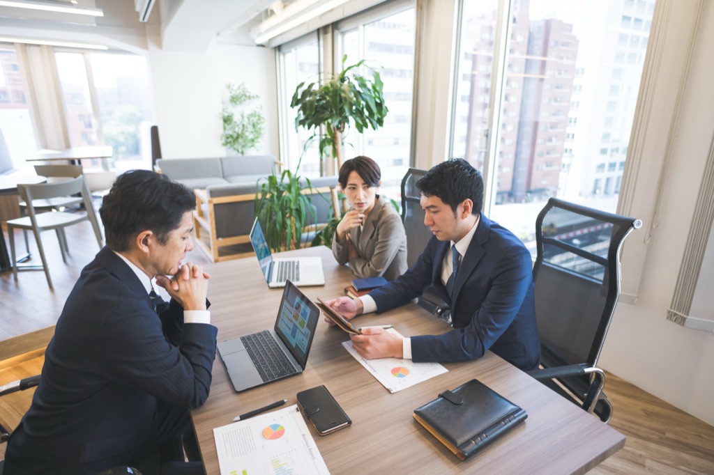 オフィスで複数人が集まり、周年の準備について相談している様子。
