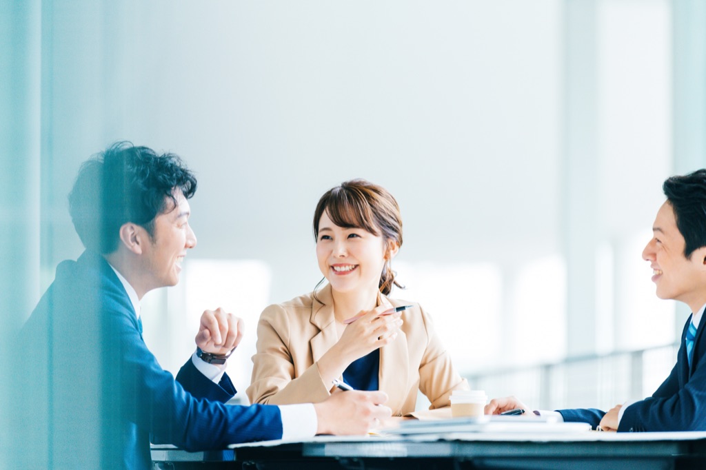 デスクをはさんで担当者と向かい合い、制作について相談している様子。