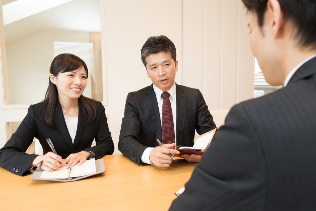 会議室で複数人が資料を前に、採用ツールについて話し合っている様子。